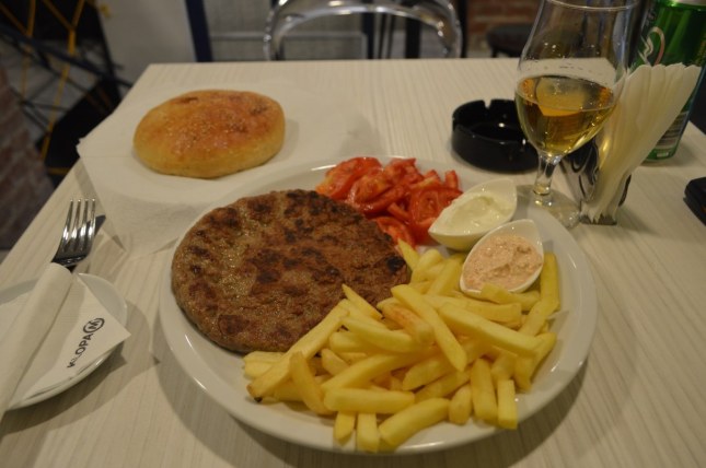 big pljeskavica with bread, urnebes, and fries